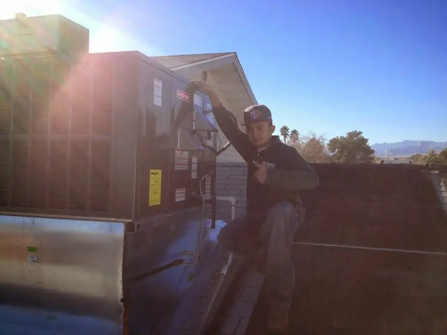HVAC technician performing AC Tune-Up on a rooftop unit in Creston